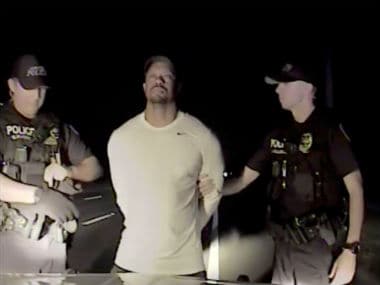 Tiger Woods is seen handcuffed and searched by police officers in this still image from police dashcam video in Jupiter, Florida. Reuters