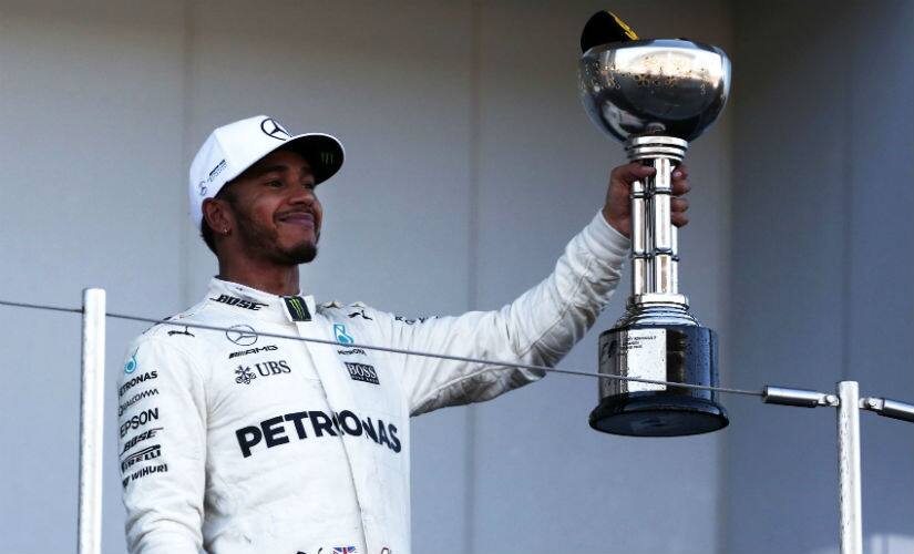 Lewis Hamilton gestures with his trophy at the podium following his win at the Japanese Grand Prix. AFP