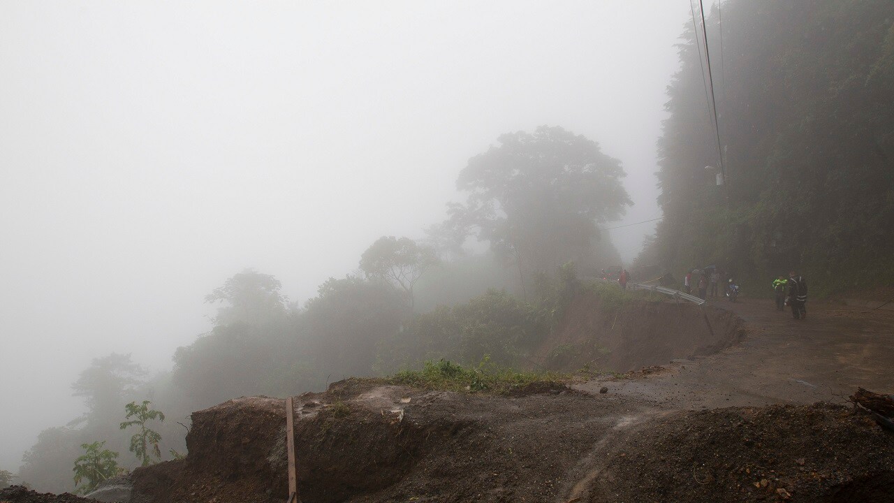 Neighbors walk under the rain past a washed out road in Alajuelita on the outskirts of San Jose, Costa Rica, Thursday, Oct. 5, 2017. Tropical Storm Nate formed off the coast of Nicaragua on Thursday and was being blamed for at least 17 deaths in Central America as it spun north toward a potential landfall on the U.S. Gulf Coast as a hurricane over the weekend. (AP Photo/Moises Castillo)