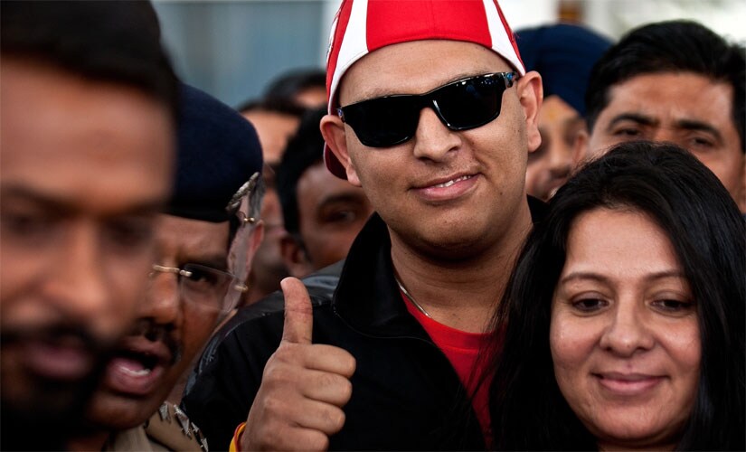 Yuvraj Singh gestures upon returning to India after treatment for a cancerous tumour in the US. His mother Shabnam Singh is in the foreground. AFP