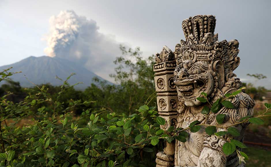 On Tuesday, life was going on largely as normal in villages surrounding Agung, with residents offering prayers as the volcano sent columns of ash and smoke into the sky. A statue on a bridge is seen as Mount Agung volcano erupts in the background. Reuters On Tuesday, life was going on largely as normal in villages surrounding Agung, with residents offering prayers as the volcano sent columns of ash and smoke into the sky. A statue on a bridge is seen as Mount Agung volcano erupts in the background. Reuters