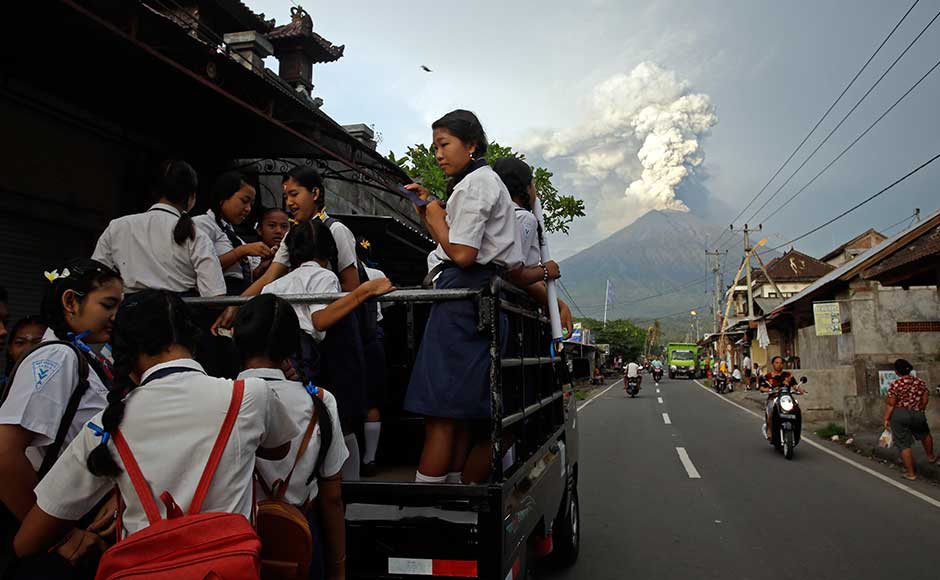 While the population in the area has been estimated at between 63,000 and 1,40,000, just over 29,000 people were registered at emergency centres, said Sutopo Purwo Nugroho, a spokesman for the Disaster Mitigation Agency. School students stand on a truck as their transport to go to school with the Mount Agung volcano spews smoke and ash. AP While the population in the area has been estimated at between 63,000 and 1,40,000, just over 29,000 people were registered at emergency centres, said Sutopo Purwo Nugroho, a spokesman for the Disaster Mitigation Agency. School students stand on a truck as their transport to go to school with the Mount Agung volcano spews smoke and ash. AP