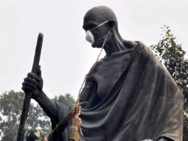 A policeman removes the anti-pollution mask from the Gandhi Statue at Gyarah Murti which was put by rebel AAP MLA Kapil Misra and BJP MLA Manjinder Singh Sirsa during their protest against smog and air-pollution. PTI