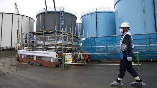 An employee walks past storage tanks for contaminated water at the tsunami-crippled Fukushima Dai-ichi nuclear power plant of the Tokyo Electric Power Co. (TEPCO). Image: AP