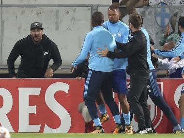 Marseille's Patrice Evra, center left, is led away by his teammate Rolando after a scuffle with Marseille supporters who trespassed into the field before the Europa League group I soccer match between Vitoria SC and Olympique de Marseille at the D. Afonso Henriques stadium in Guimaraes, Portugal, Thursday, Nov. 2, 2017. Evra was shown a red card before the start of the match for his involvement in the incident. (AP Photo/Luis Vieira)