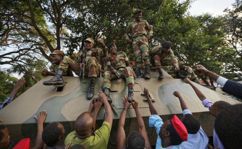 Zimbabweans reach out to touch and thank army soldiers, as they celebrate outside the parliament building on Tuesday. AP