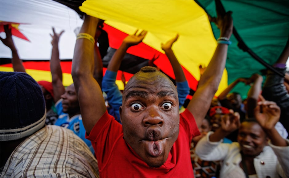 A happy protester pulls a face as he and others stand under a large national flag, at the demonstration of tens of thousands at Zimbabwe Grounds in Harare. AP A happy protester pulls a face as he and others stand under a large national flag, at the demonstration of tens of thousands at Zimbabwe Grounds in Harare. AP