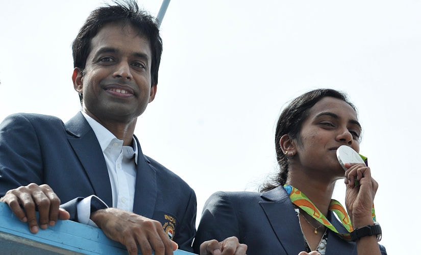 Indian badminton player and Olympic silver medalist P.V Sindhu (R) and her coach P. Gopichand take part in a parade after arriving home from the Rio Olympics in Hyderabad on August 22, 2016. India swelled with pride August 20 after badminton champion P.V. Sindhu became the first woman in the country's history to win an Olympic silver medal. / AFP PHOTO / NOAH SEELAM