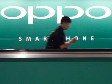 A commuter using his mobile phone passes an advertisement of Chinese smartphone maker Oppo. Image: Reuters