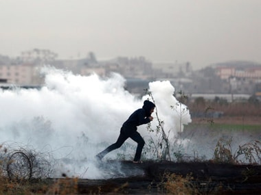 A Palestinian protester runs for cover from teargas fired by Israeli troops during clashes on the Israeli border with Gaza. AP