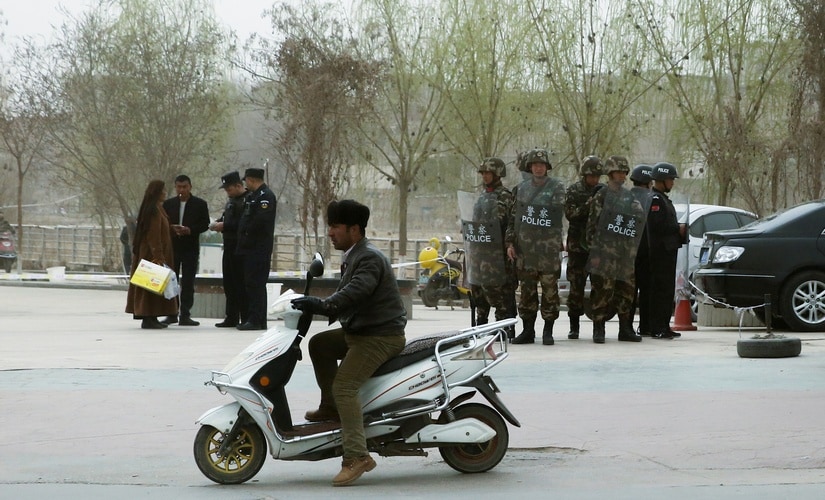 In this file image, Police officers check the identity cards of people as security forces keep watch in a street in, Xinjiang Uighur Autonomous Region, China. Reuters