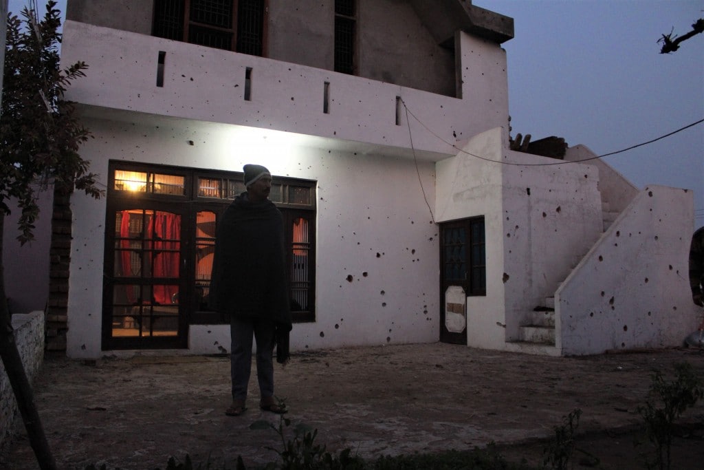 Ajit Singh, another resident from Bera stands outside his house in Bera village. Heavy mortar shelling is visible on the walls of his house. Image by Sameer Yasir.