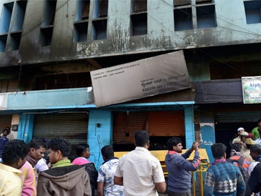 Passer-bys look on at the fire site where a fire broke out at a bar-cum-restaurant, in Bengaluru on Monday. PTI