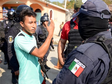 A relative argues with a police officer, near where an exchange of gunfire took place between residents and members of a local, self-appointed community police force which according to local media, left 11 dead in La Concepcion, Guerrero. Reuters