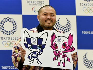 Ryo Taniguchi, winning designer of the official mascots for the 2020 Olympics (L) and Paralympics Games, poses for photographers at an elementary school in Tokyo on February 28, 2018. Tokyo on February 28 unveiled its long-awaited mascot for the 2020 Olympic Games: a futuristic blue-checked, doe-eyed character with pointy ears and "special powers" that was picked by schoolchildren across mascot-mad Japan. / AFP PHOTO / TORU YAMANAKA