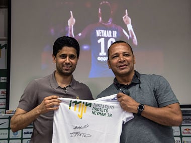 French football team Paris Saint-Germain's (PSG) Qatari president Nasser Al-Khelaifi (L) and Neymar Santos, father of Brazilian superstar and PSG's footballer Neymar Junior, pose for pictures holding a t-shirt of Neymar Junior Institute project, during a press conference, in Praia Grande, Sao Paulo, Brazil on March 13, 2018. Nasser Al-Khelaifi arrived in Brazil to visit the world's most expensive player, Neymar, who broke a bone in his right foot on February 25 and faces weeks of recuperation following surgery. The visit also takes place amid rumors swirling about the striker's intention to quit PSG. / AFP PHOTO / NELSON ALMEIDA