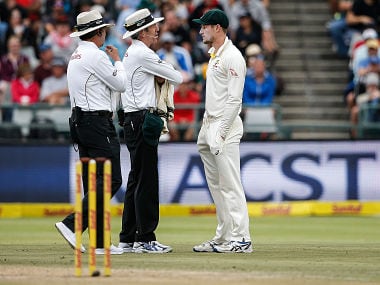 Australian fielder Cameron Bancroft (R) is questioned by Umpires Richard Illingworth (L) and Nigel Llong (C) during the third day of the third Test cricket match between South Africa and Australia at Newlands cricket ground on March 24, 2018 in Cape Town. / AFP PHOTO / GIANLUIGI GUERCIA
