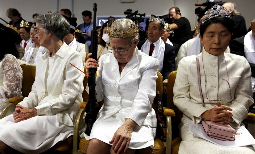 A woman wears a crown and holds an unloaded weapon as she bows her head during services at the World Peace and Unification Sanctuary. AP
