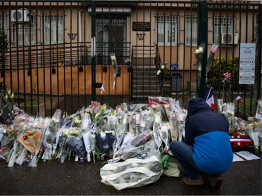 A man places flowers at the main gate of the police headquarters in Carcassonne. AP