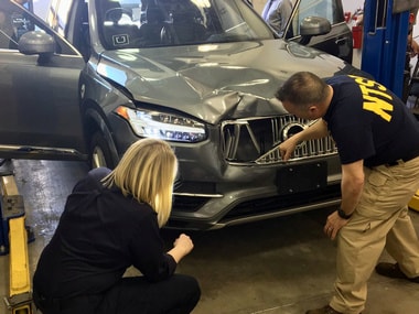 Investigators examine a self-driving Uber vehicle involved in a fatal accident