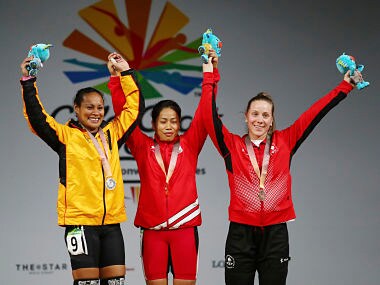 India's women's 53Kg Weightlifting Gold medalist Sanjita Chanu, center, with Papua New Guinea's Silver medalist Dika Loa Toua, left, and Canada Bronze medalist Rachel Leblanc-Bazinet wave during the medal ceremony at the Commonwealth Games, in Gold Coast, Australia, Friday, April 6, 2018. (AP Photo/Manish Swarup)