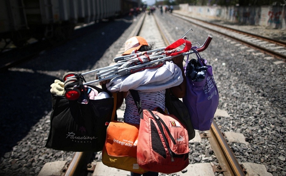 A Central American migrant, moving in a caravan through Mexico, descends from a freight train as she carries her belongings on a railway track after stopping the train on a rail line, in Irapuato, Guanajuato state, Mexico. REUTERS A Central American migrant, moving in a caravan through Mexico, descends from a freight train as she carries her belongings on a railway track after stopping the train on a rail line, in Irapuato, Guanajuato state, Mexico. REUTERS