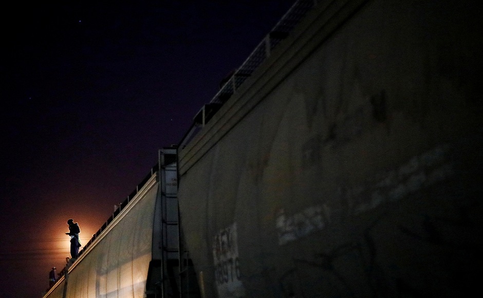 A Central American migrant, moving in a caravan through Mexico, stands on a wagon of a freight train as he embarks on a new leg of their travels, in Tlaquepaque, in Jalisco state, Mexico. REUTERS A Central American migrant, moving in a caravan through Mexico, stands on a wagon of a freight train as he embarks on a new leg of their travels, in Tlaquepaque, in Jalisco state, Mexico. REUTERS