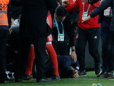Besiktas coach Senol Gunes is on the floor after being hit by an object. Reuters