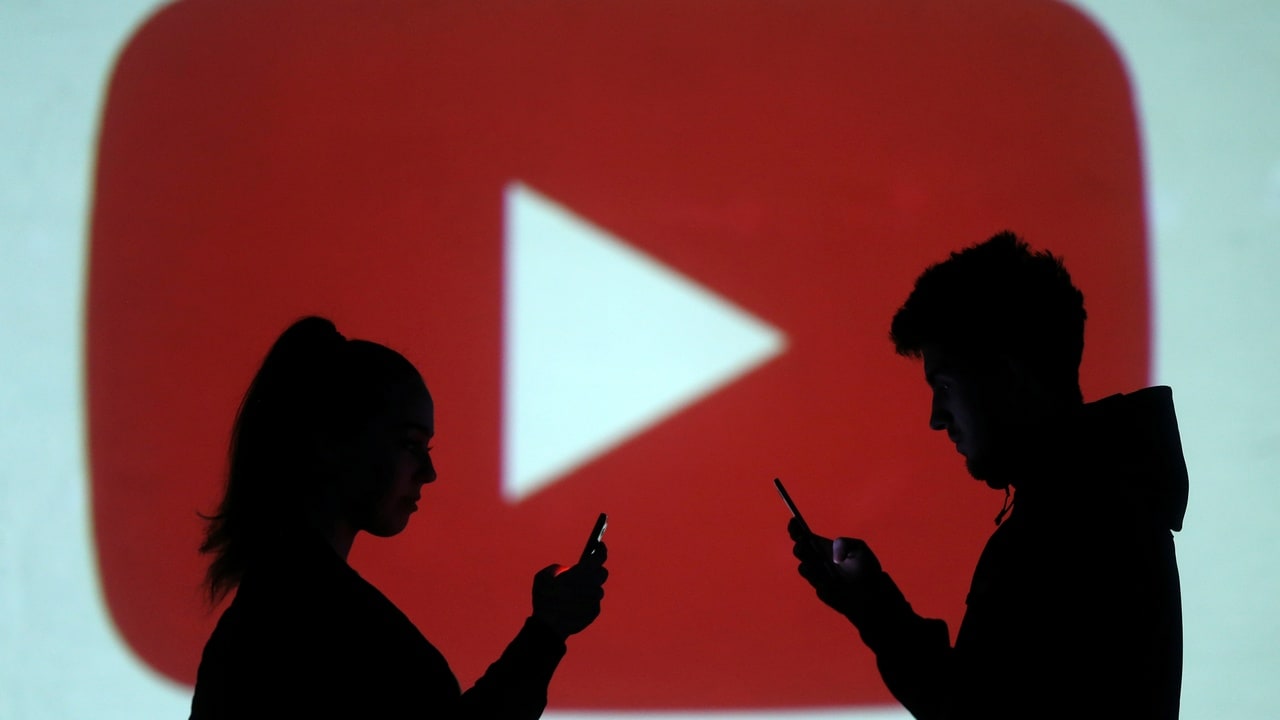 Silhouettes of mobile users are seen next to a screen projection of Youtube logo in this picture illustration taken March 28, 2018. REUTERS/Dado Ruvic/Illustration - RC1B4475F2D0