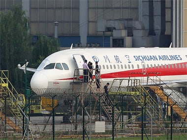 Employees checking a Sichuan Airlines Airbus A319 after an emergency landing, as a broken cockpit window (L) is covered. AFP