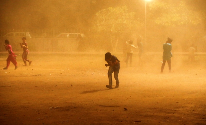 Children cover themselves during a dust storm in New Delhi, India May 13, 2018. Reuters