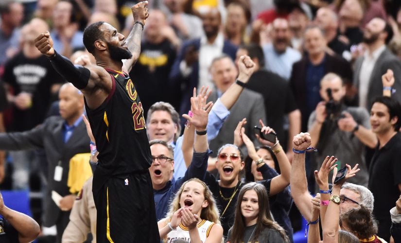 LeBron James stands on the scorer's table after hitting the final shot to win the game for Cleveland Cavaliers. Reuters