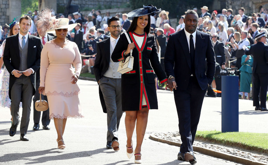 Idris Elba and Sabrina Dhowre followed by Oprah Winfrey arrive at St George's Chapel. Reuters