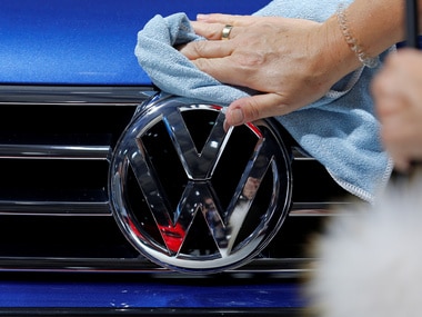 A worker shines the grill of a Volkswagen car displayed on media day at the Paris auto show. Image: Reuters
