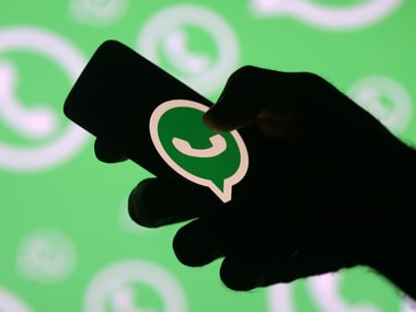 A man poses with a smartphone in front of displayed Whatsapp logo. Image: Reuters
