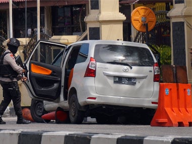 An officer inspects a minivan used in the attack at the regional police headquarters in Indonesia. AP 