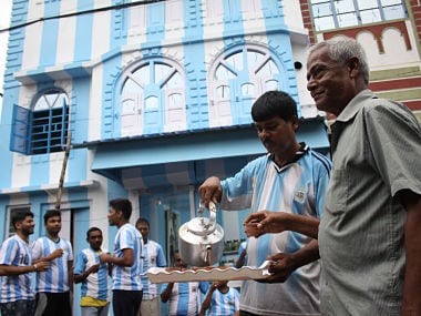 Shib Shankar Patra (2R), football fan of Argentina team, serves tea to fans and customers in front of his apartment painted in blue-and-white, ahead of the upcoming 2018 World Cup, on June 11, 2018. A die-hard Argentina fan in India has painted his house in the team's blue and white colours ahead of the World Cup, saying his love for Lionel Messi's men knows no bounds. Kolkata resident Shib Shankar Patra's passion for Argentina began during the 1986 World Cup when Diego Maradona helped the team win the coveted trophy. / AFP PHOTO / -