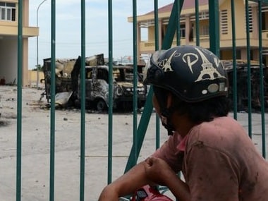 In Vietnam, a motorist looks at charred vehicles burned by protesters at a fire. AP