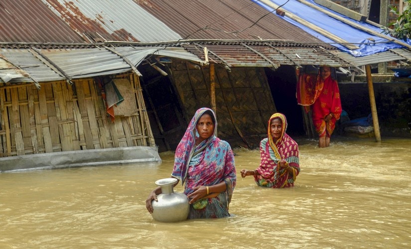 Villagers carry clean water as they wade across flood-affected areas at Nilambazar village, in Karimganj, Assam, on Sunday. PTI