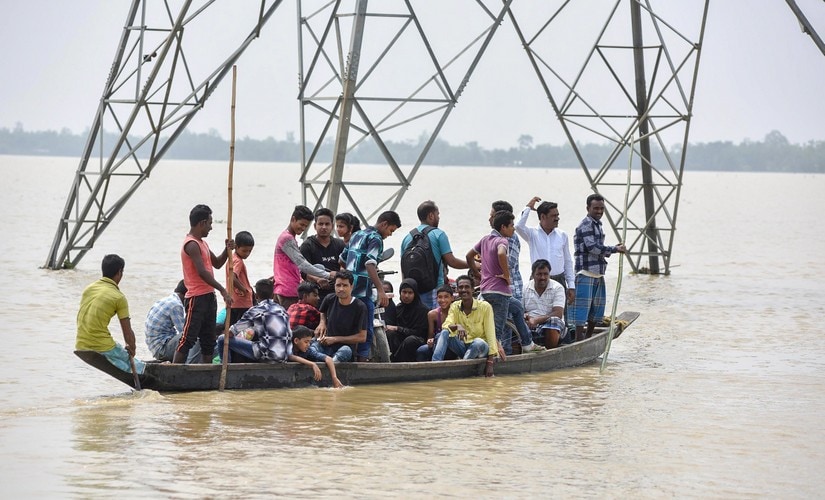 Villagers travel in a boat to cross across flood water, in Hojai, Assam, on Sunday.