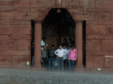 People take shelter under the arch of Raisina Hills during rainfall, in New Delhi . PTI