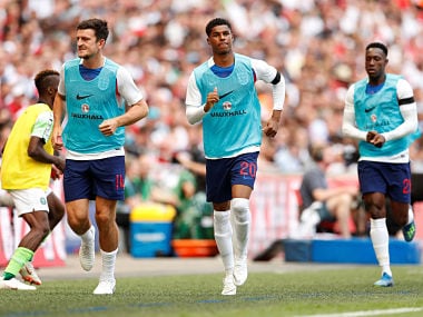 England's Harry Maguire and Marcus Rashford warm up on the sideline during a match. Reuters