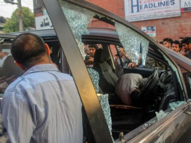 Police and locals inspect the damaged vehicle after suspected militants shot dead Shujaat Bukhari. PTI