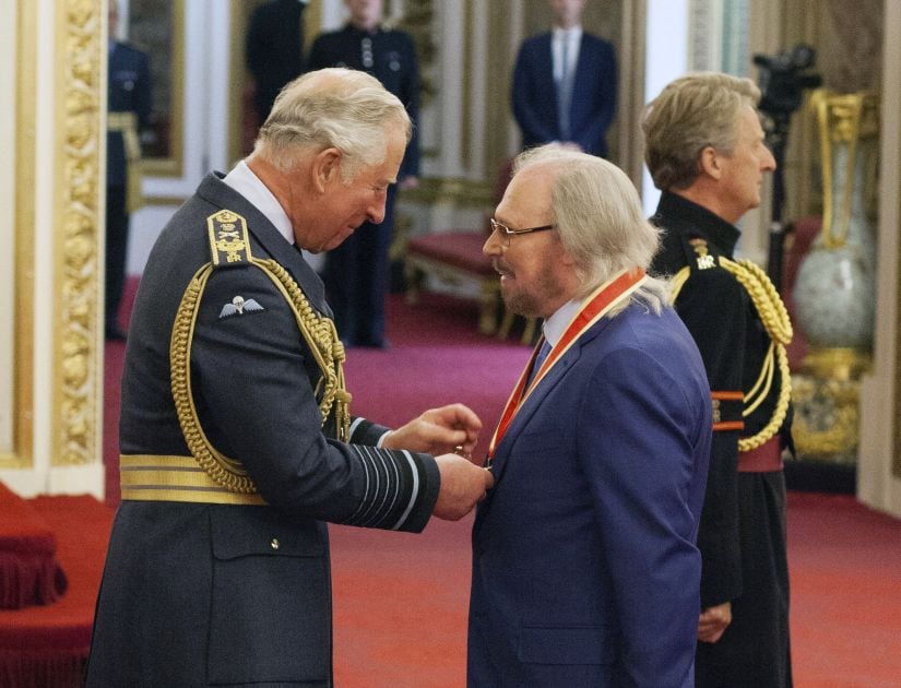 Singer and songwriter Barry Gibb talks with Prince Charles, left, during an Investiture ceremony to award a knighthood to Gibb, at Buckingham Palace in London, Tuesday June 26, 2018. (Dominic Lipinski/PA via AP)