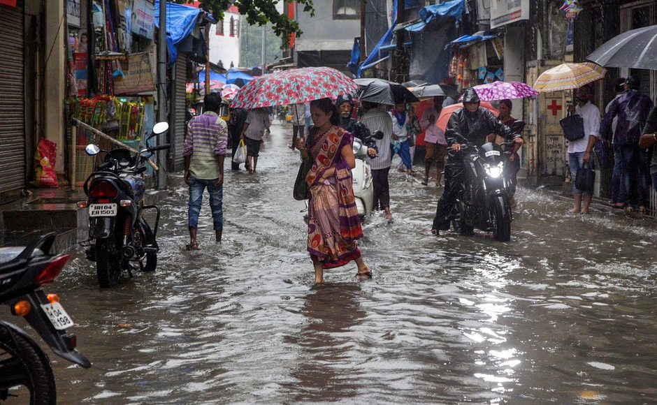 People walk through a water-logged street after heavy rains, in Thane on Monday. PTI People walk through a water-logged street after heavy rains, in Thane on Monday. PTI