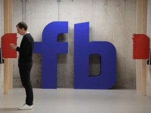A man waits for an elevator in front of a logo at Facebook's headquarters in London, Britain, December 4, 2017. Image: Reuters