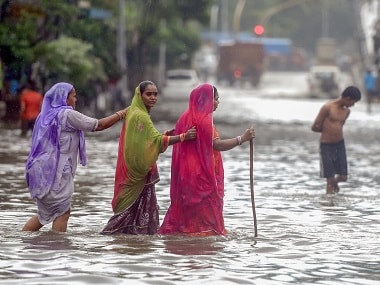 People cross the waterlogged street at King Circle after heavy rains in Mumbai. PTI