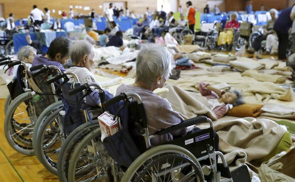 Elderly people from a nursing home take shelter following a heavy rain, in Soja, Okayama prefecture, western Japan. AP