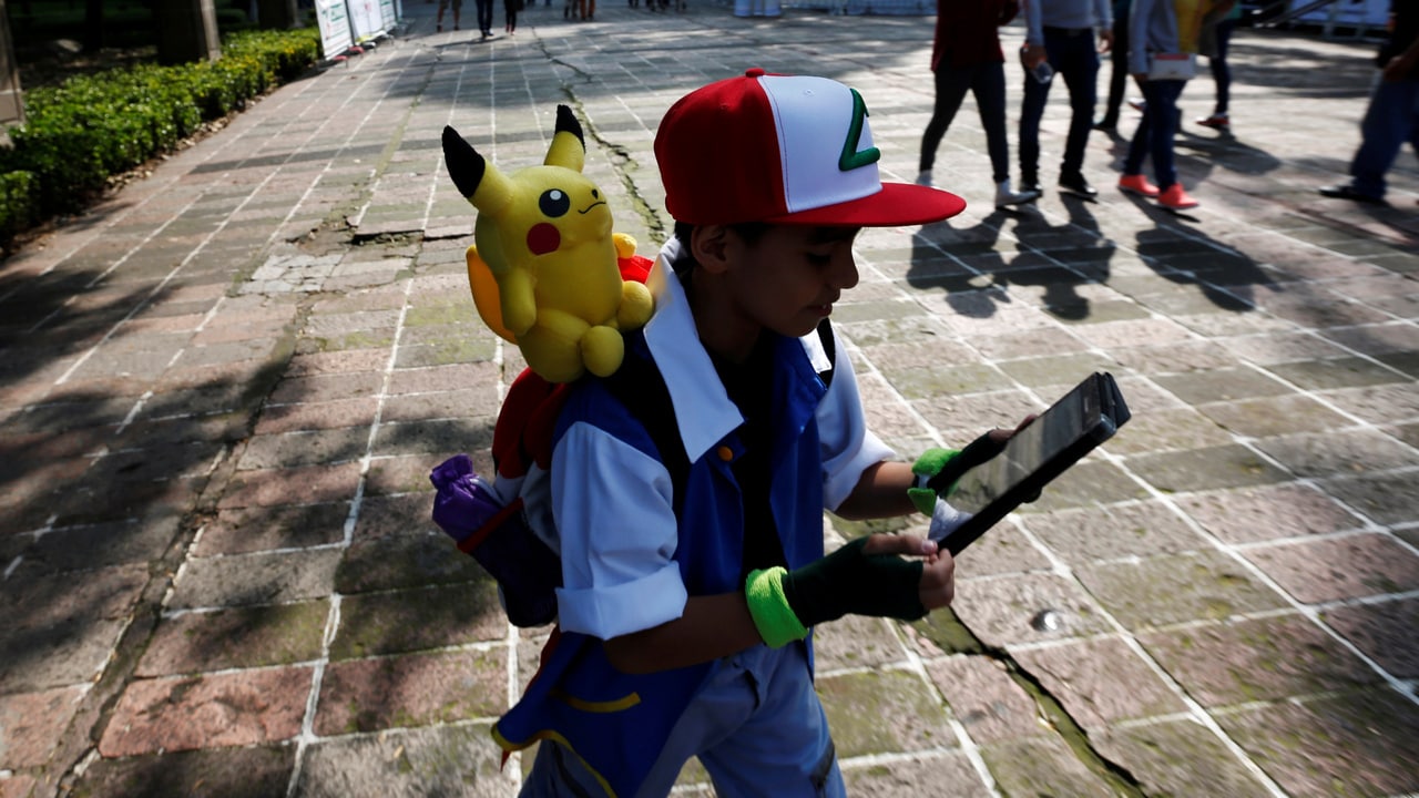 A child carries a Pokemon character, Pikachu, on his shoulder as he plays Pokemon Go during a gathering to celebrate