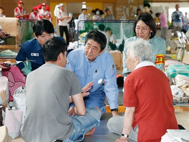 Japanese Prime Minister Shinzo Abe, center, listens to an evacuee during a visit to an evacuation center in Kurashiki, Okayama prefecture. AP